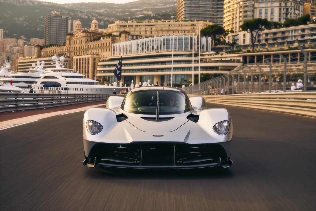 Close-up of the front of an orange Lamborghini hypercar parked on a road, with a visible emblem and sunlight reflecting off the car’s surface.