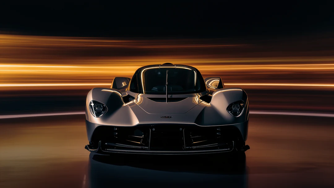 Long, wavy, orange and yellow light trails evoke the dynamic speed of hypercars, captured against a black background as abstract lines and curves.